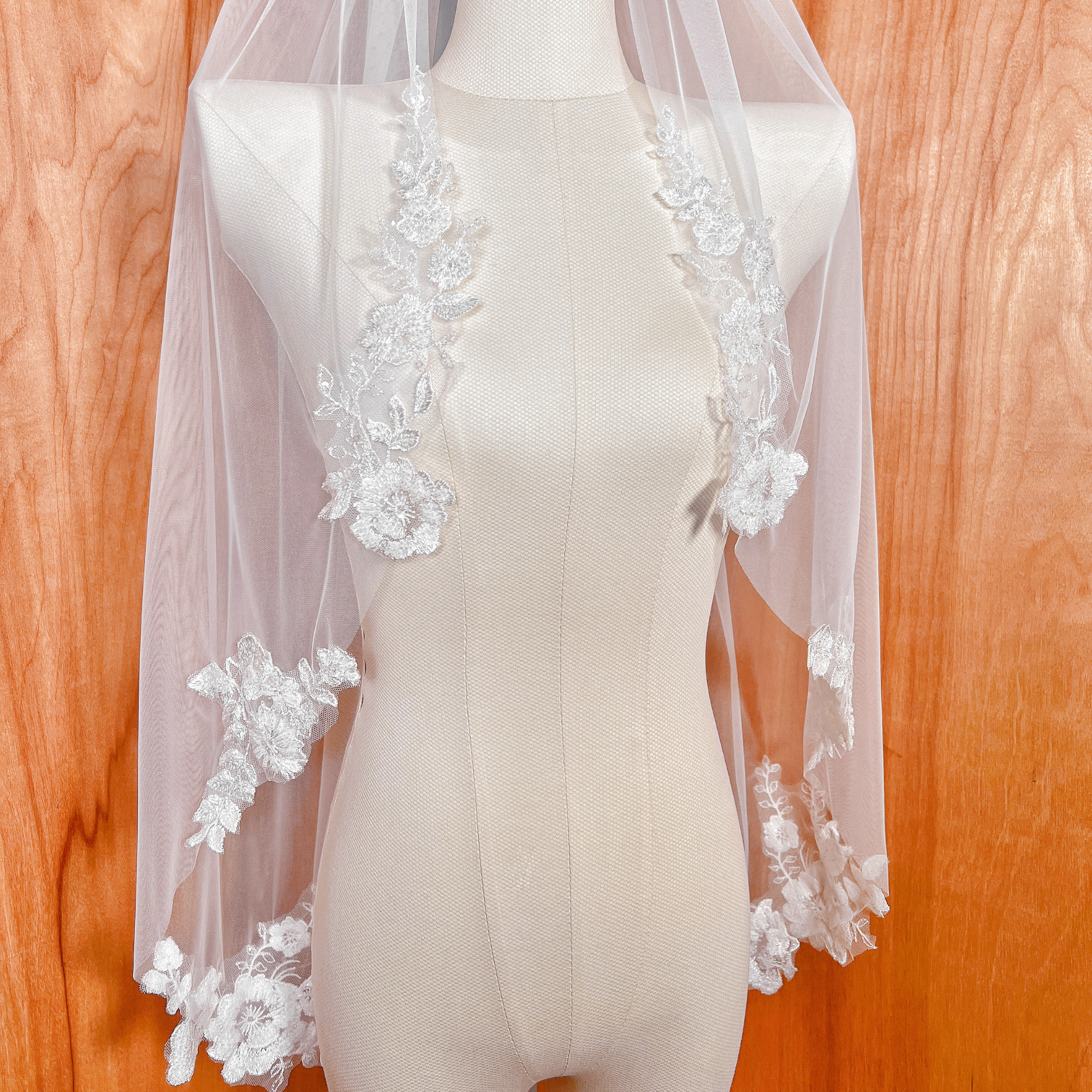 Elegant ivory fingertip length floral beaded lace wedding veil showcasing delicate embroidery and beads.