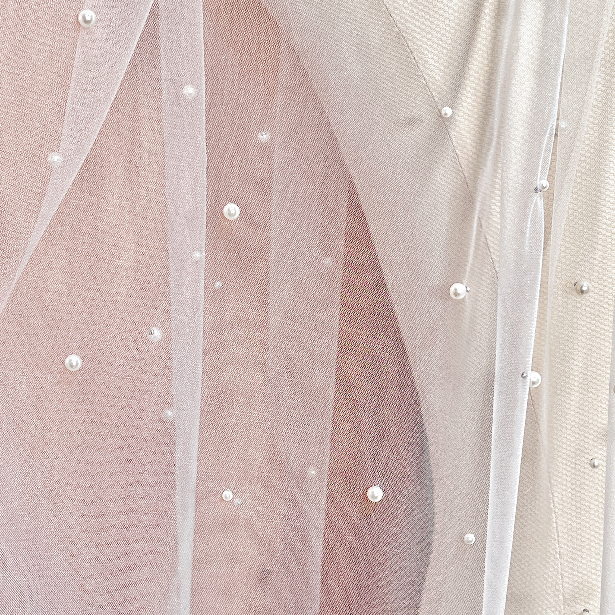 Close-up of the intricate scattered pearl embellishments on a fingertip-length wedding veil, highlighting the high-quality 4mm pearls and raw-edge finish.