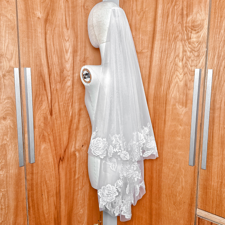 Classic ivory two tier floral lace wedding veil shown in fingertip length for bridal styling.