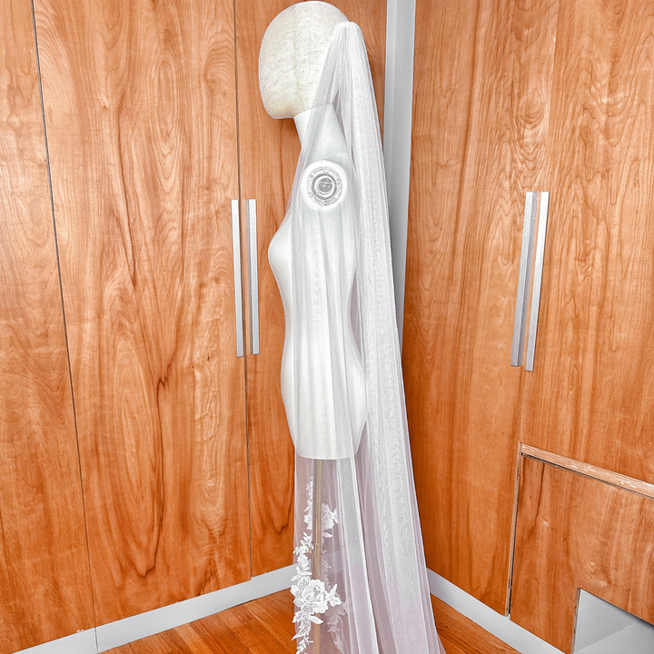 A ivory lace edge wedding veil showing on a mannequin.
