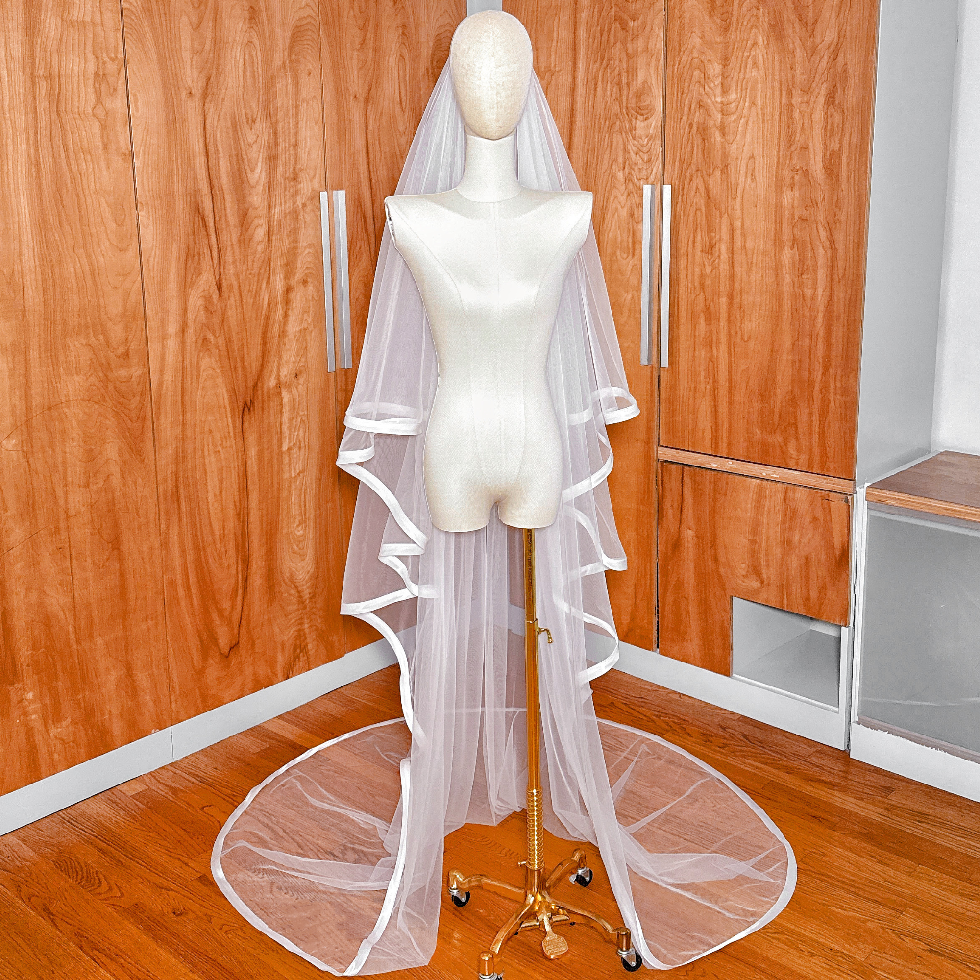 Full-length view of an ivory 1 inch ribbon edge cathedral veil featuring a traditional blusher.