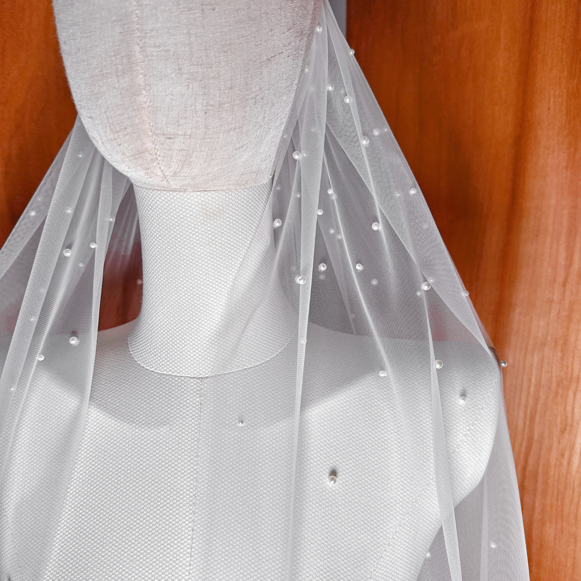 Close-up of ivory scattered pearl veil showing the delicate placement of pearls on soft bridal tulle.