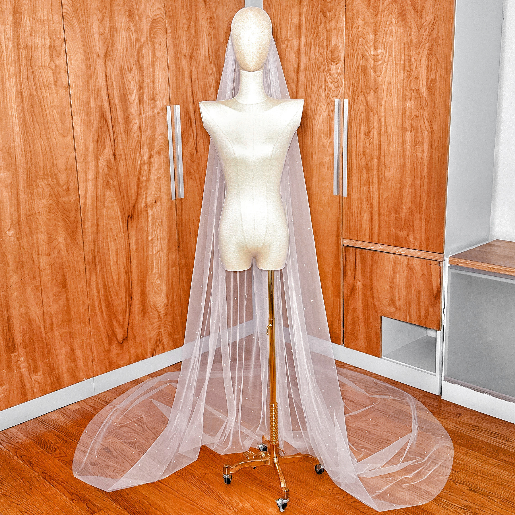 A dramatic cathedral-length veil with pearls scattered across the wide train, creating a stardust effect.