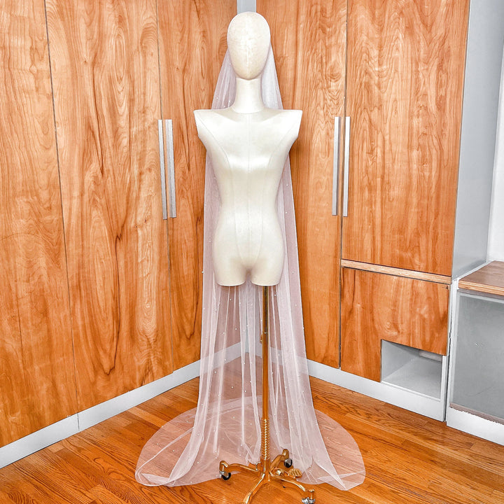An ivory scattered pearl wedding veil featuring a clean-cut edge and delicate pearl embellishments on soft bridal tulle.