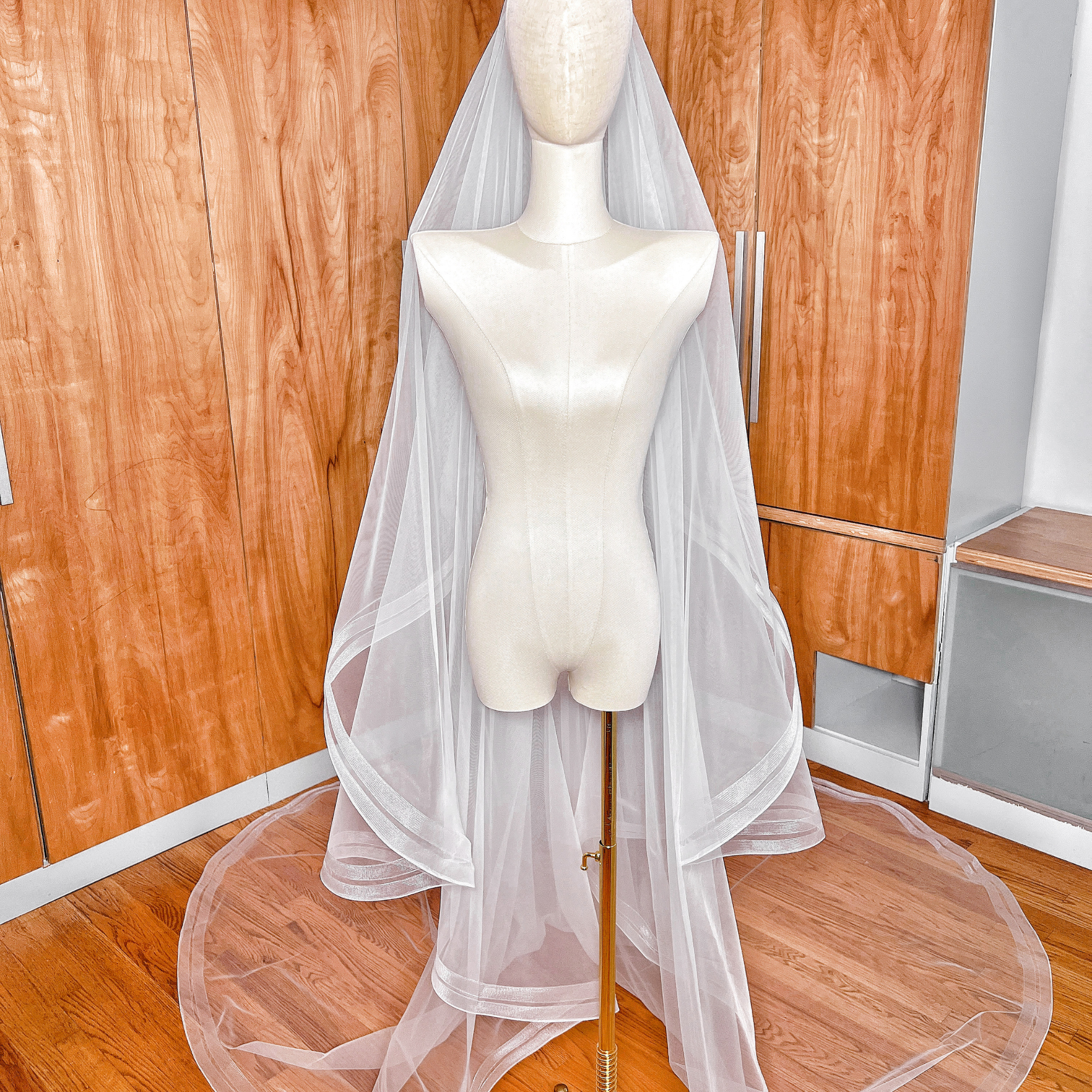 Cathedral length two tier bridal veil with double horsehair trim on a mannequin stand.