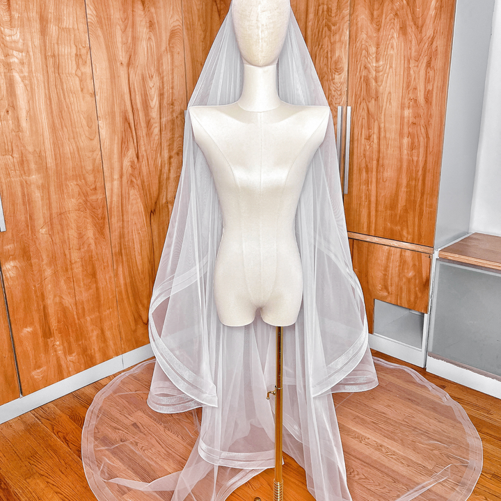 Cathedral length two tier bridal veil with double horsehair trim on a mannequin stand.