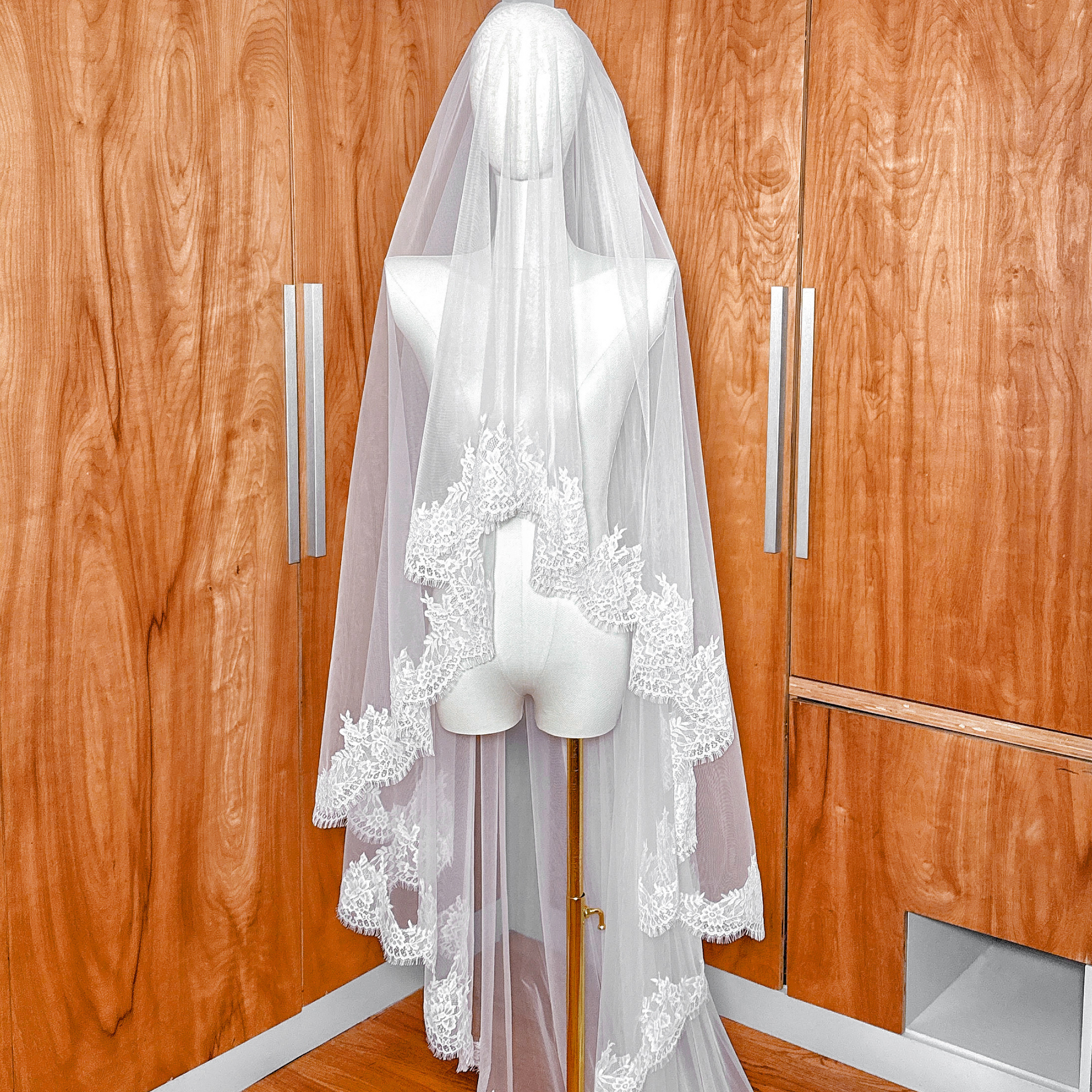 Ivory two tier Chantilly lace veil in cathedral length shown on a mannequin against a neutral studio background.