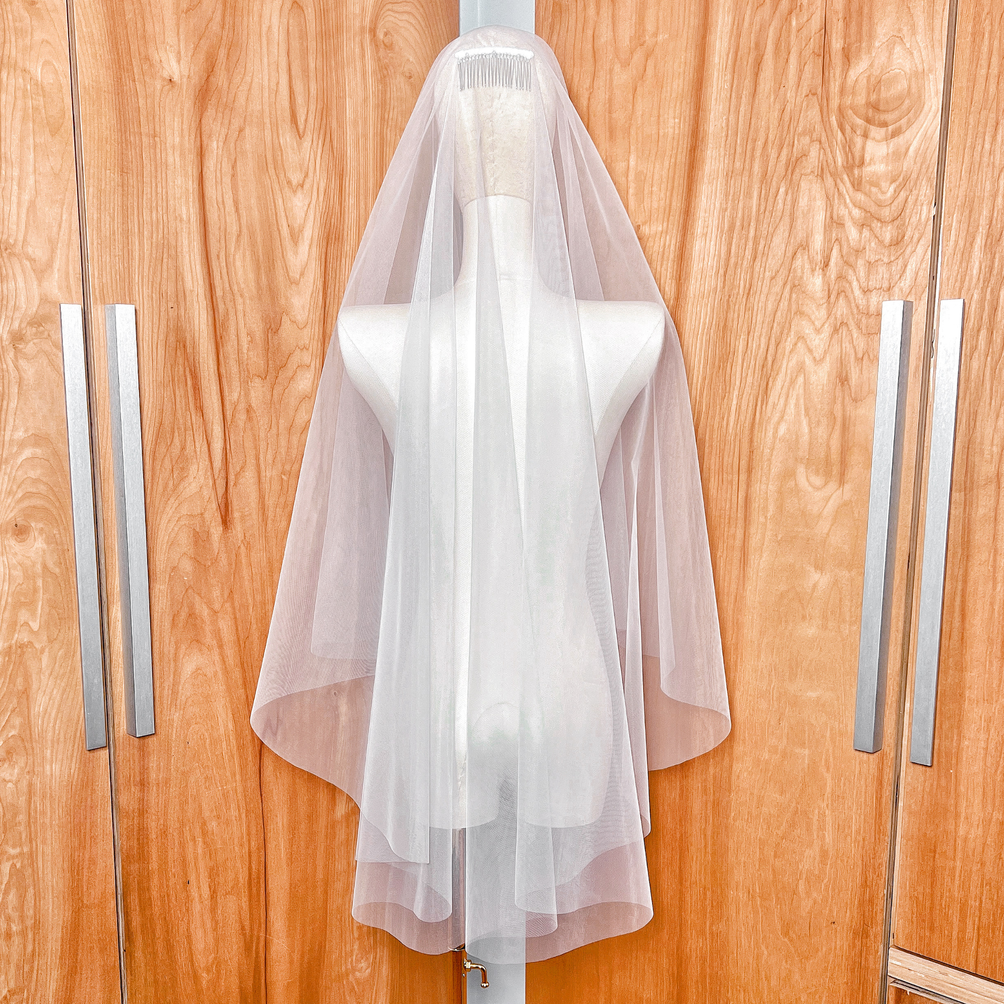 Back view of a double-layered fingertip length bridal veil featuring a classic raw cut edge in ivory tulle.