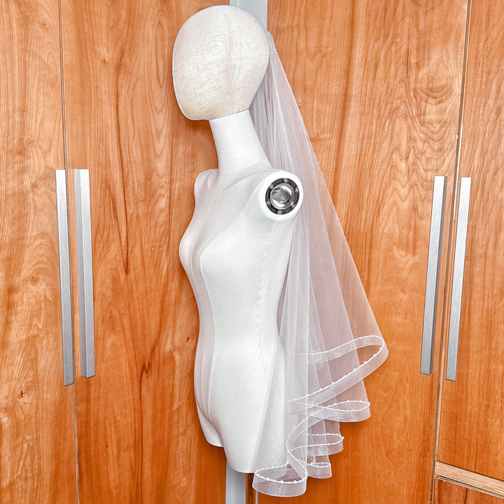 Two-tier fingertip length horsehair wedding veil with ivory pearl trim detailing.