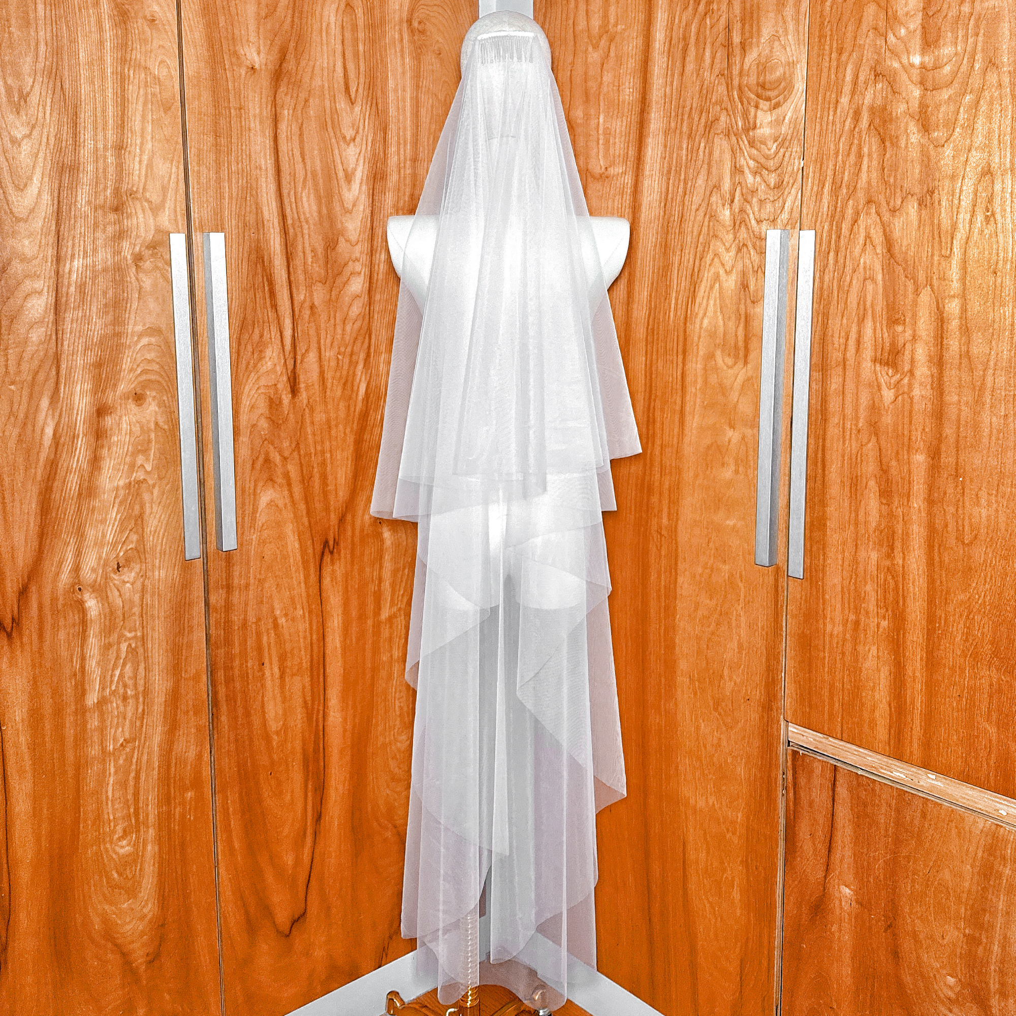 Detailed view of the soft tulle on a two-tier waltz length wedding veil with a blusher and a modern raw edge design.