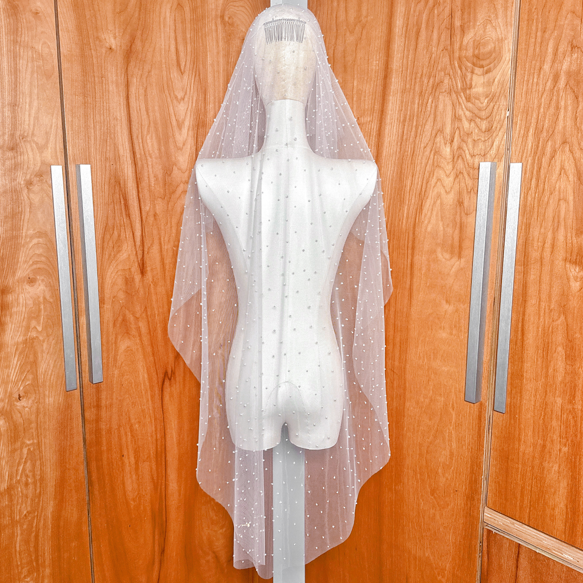 Back view of the scattered pearl blusher veil on a mannequin, highlighting the two-tier design and how the pearls cascade to knee length.
