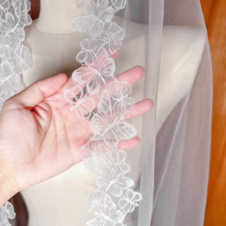 Detailed close-up of the intricate butterfly lace motifs on the edge of the mantilla veil.