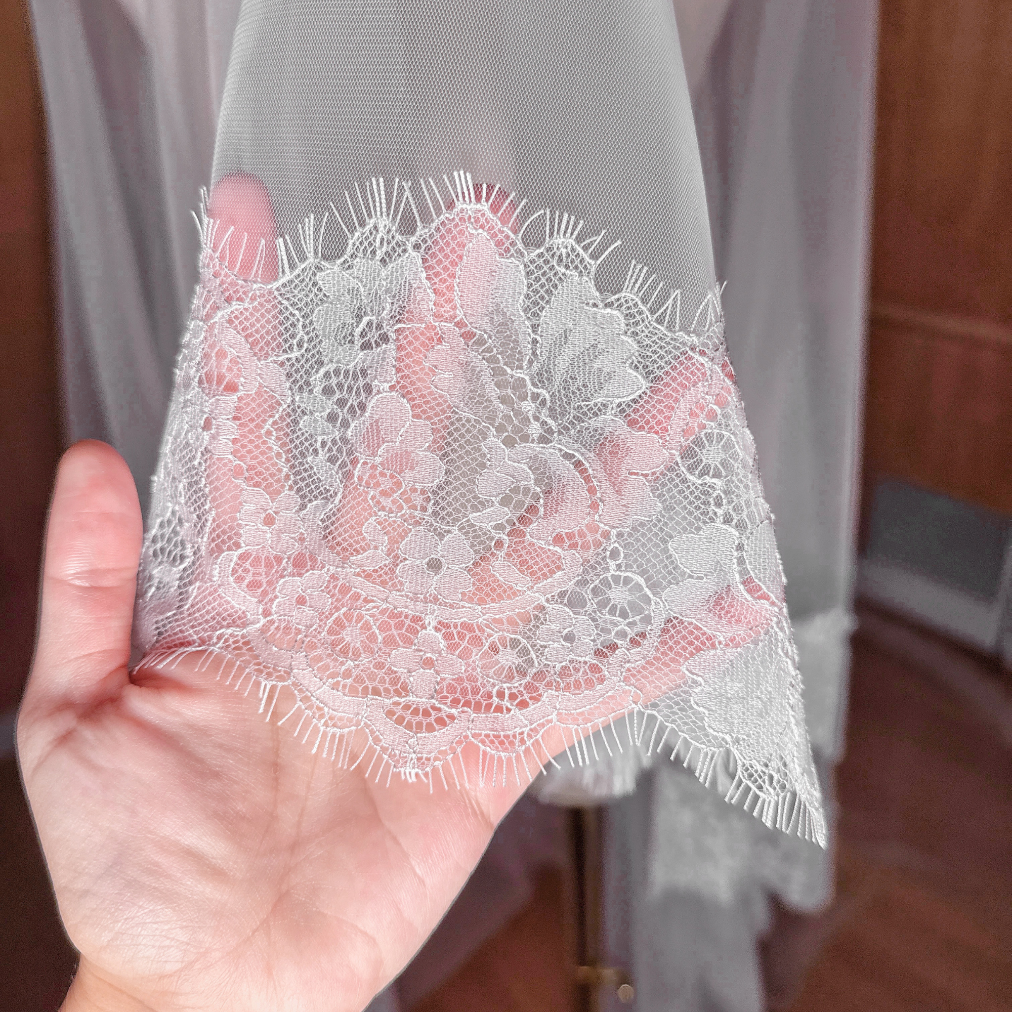 Detailed view of a Chantilly lace wedding veil with a face-covering blusher tier.
