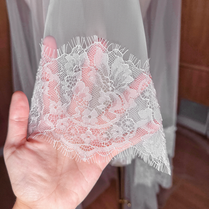 Detailed view of a Chantilly lace wedding veil with a face-covering blusher tier.