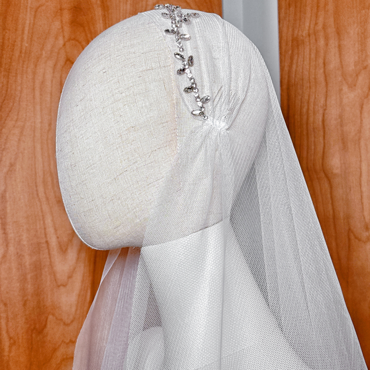 Detail shot of the soft bridal tulle and beaded leafy patterns of the fingertip length Juliet cap veil.