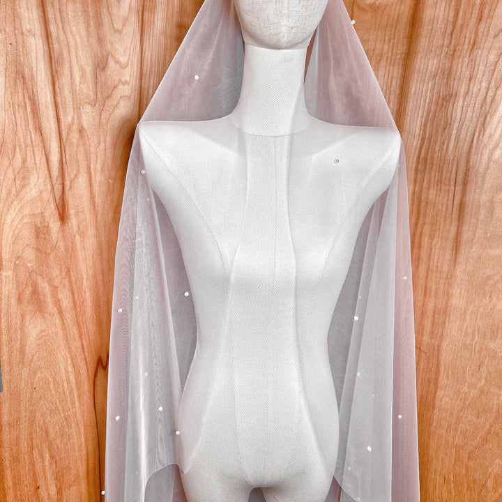 Side profile of a cathedral length allover pearl wedding veil highlighting the length and density of the pearl accents.