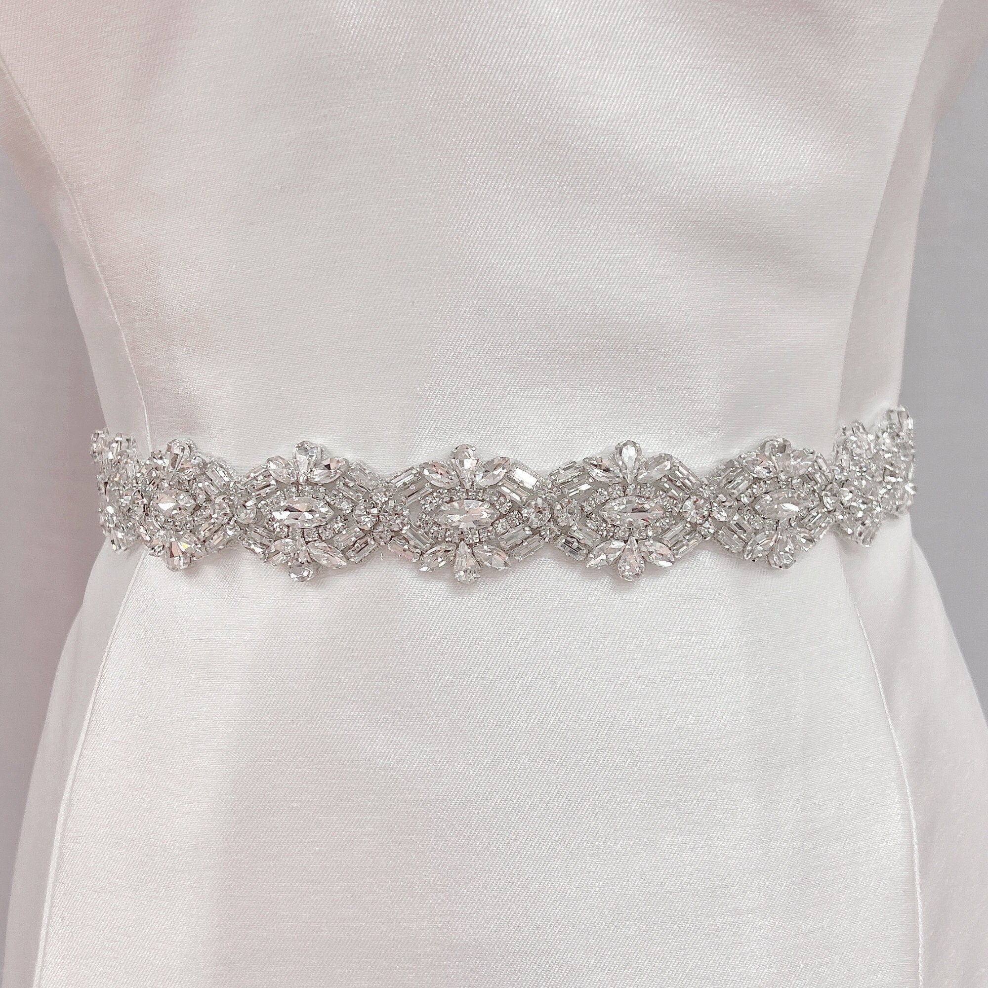 Front view of a luxury Art Deco beaded bridal belt with silver embroidery displayed on a cream fabric mannequin.