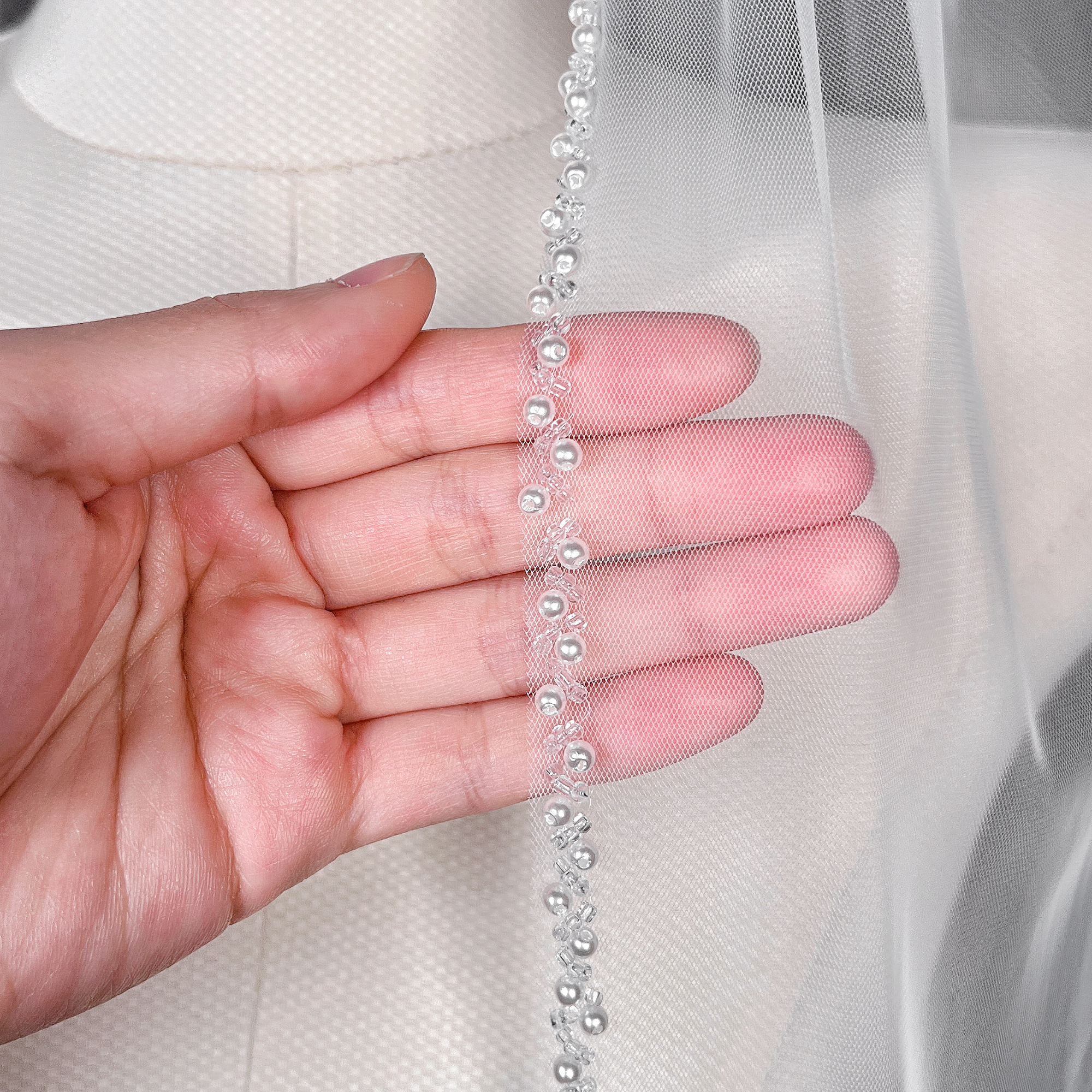 Close-up details of the intricate trim on a cathedral length beaded edge wedding veil.