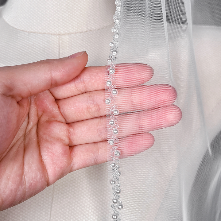 Close-up details of the intricate trim on a cathedral length beaded edge wedding veil.