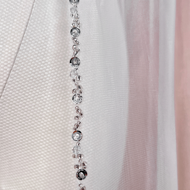 Detailed view of the intricate trim on a beaded edge wedding veil in waltz length.