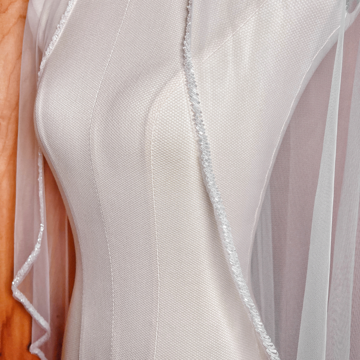 Intricate frosted bugle beads detailing the border of a fingertip length beaded edge wedding veil.