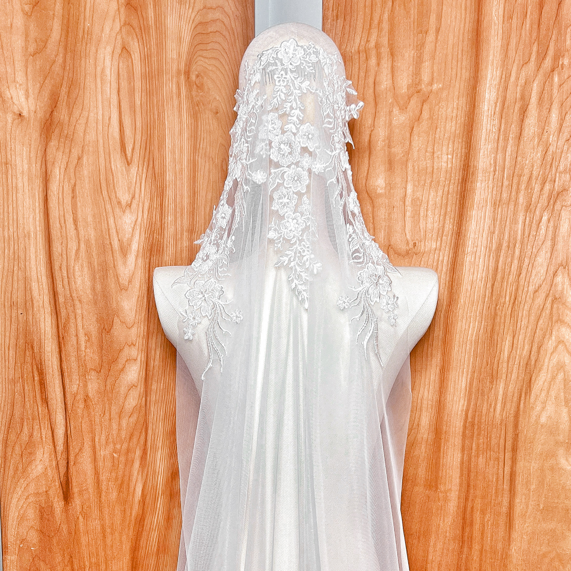 Macro shot of delicate beadwork and embroidery on a mantilla style wedding veil, highlighting the craftsmanship of the lace border.