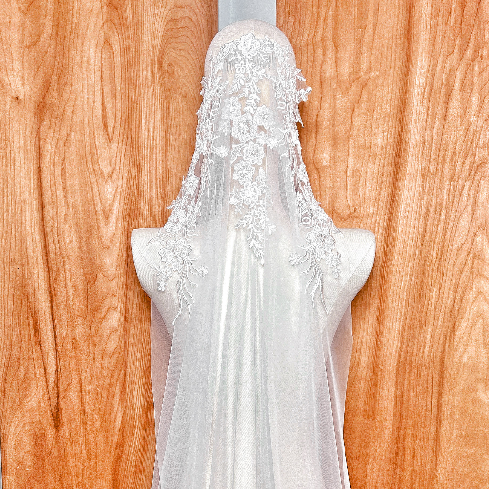 Macro shot of delicate beadwork and embroidery on a mantilla style wedding veil, highlighting the craftsmanship of the lace border.
