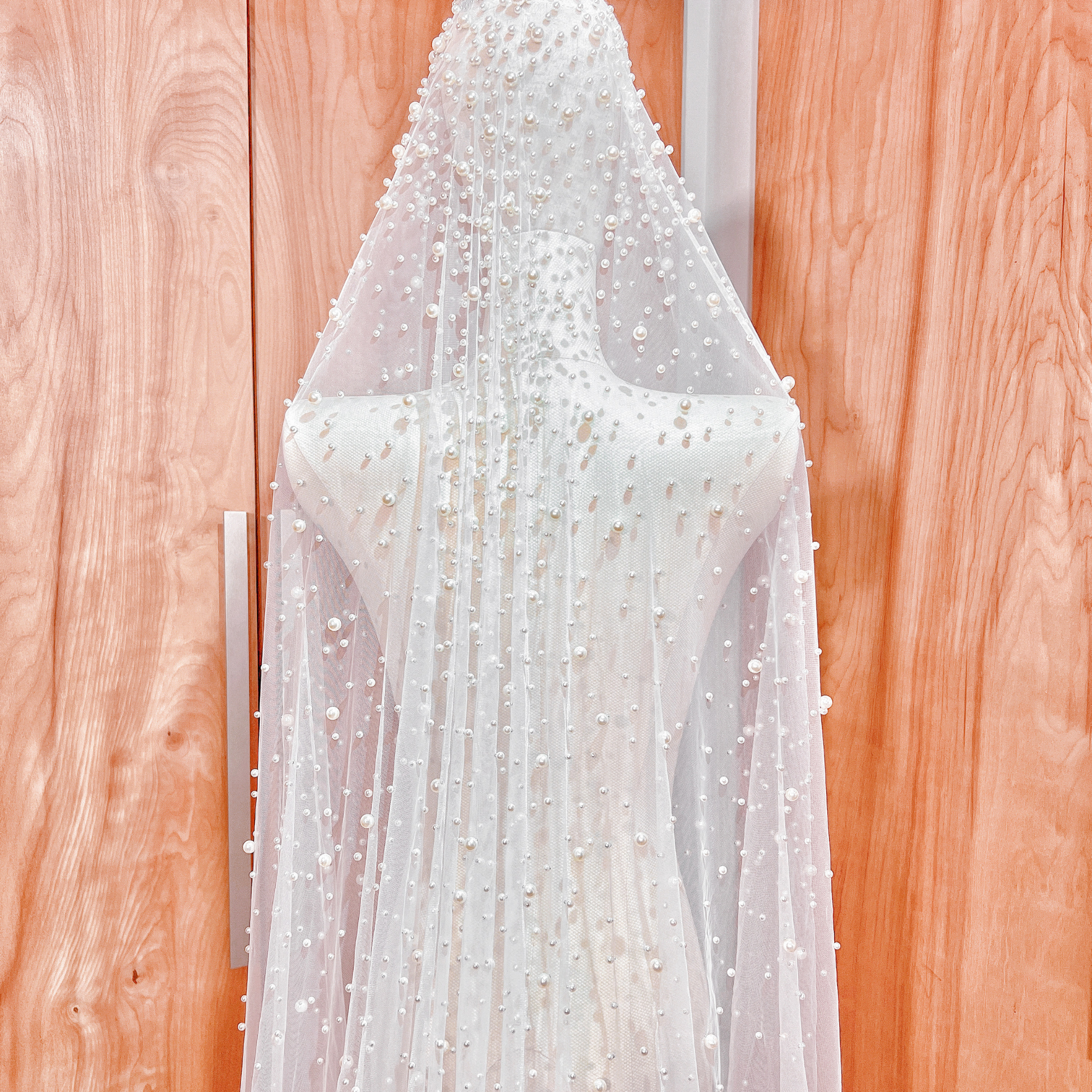 Luxury bridal accessory featuring a pearl studded mantilla wedding veil in a full cathedral length.