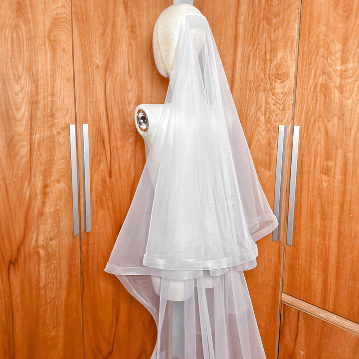 A high-quality 1 1/2" horsehair trim wedding veil with blusher in cathedral length showcased on a bridal mannequin.