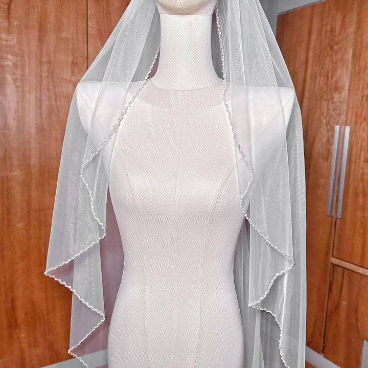 Detailed view of the pearl trim craftsmanship on a sheer angel cut cathedral bridal veil.