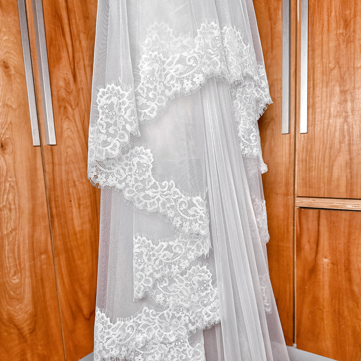Detailed scalloped Chantilly lace edge of a two tier cathedral veil displayed on a mannequin.