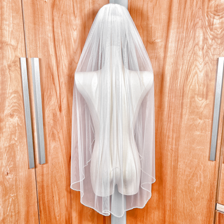 Back view of a fingertip length crystal beaded wedding veil on display.