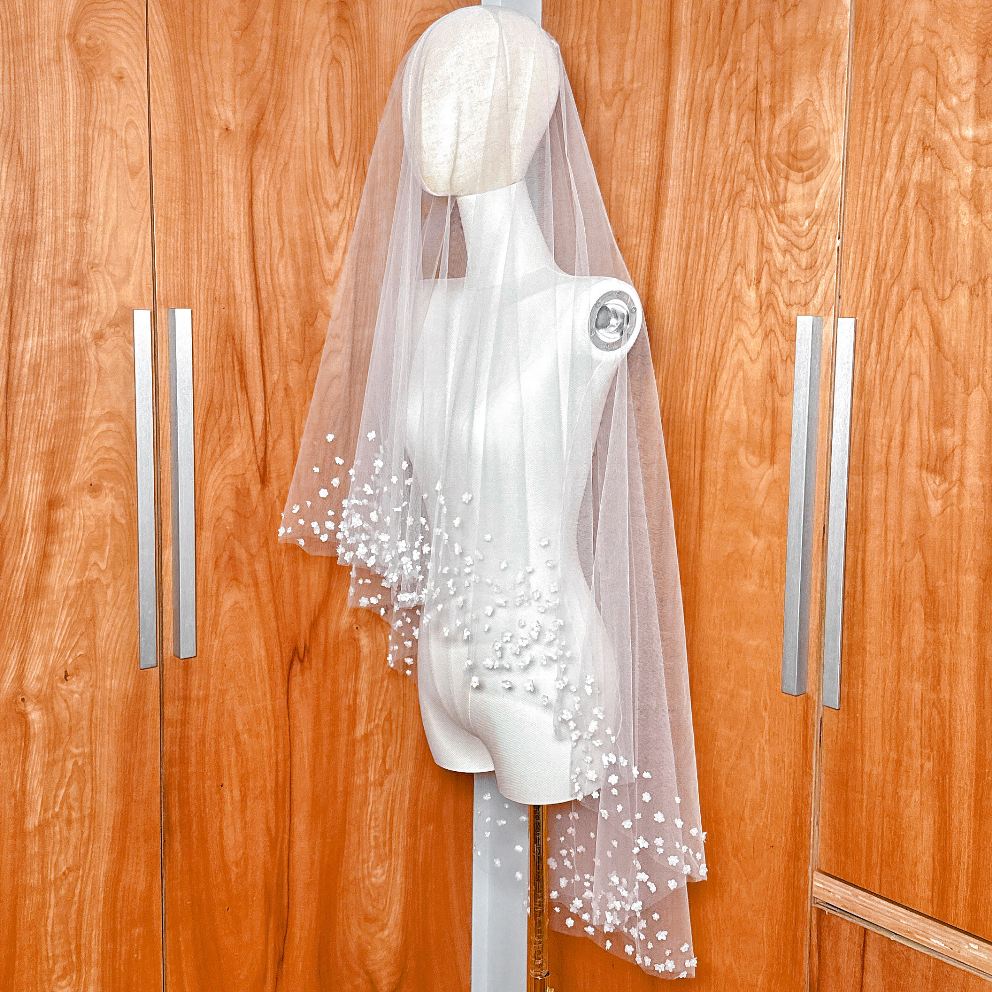 Studio display of the luxury 3D silk blossom bridal veil with blusher against a warm wooden backdrop.