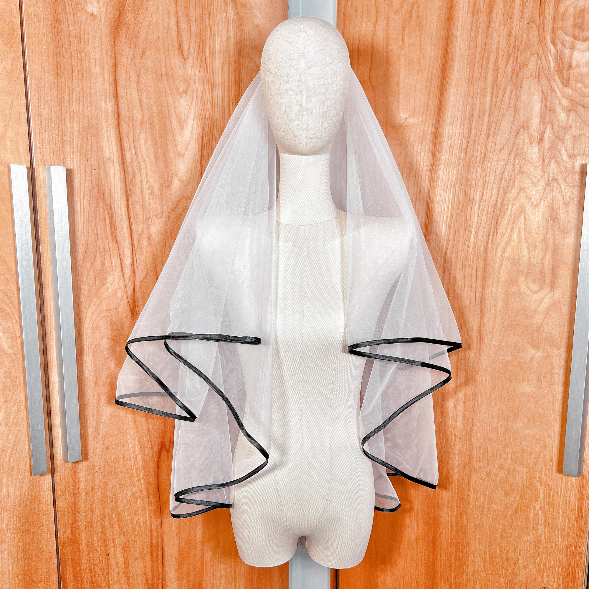 Elegant two-tier black ribbon edge wedding veil shown from the front on a mannequin display.