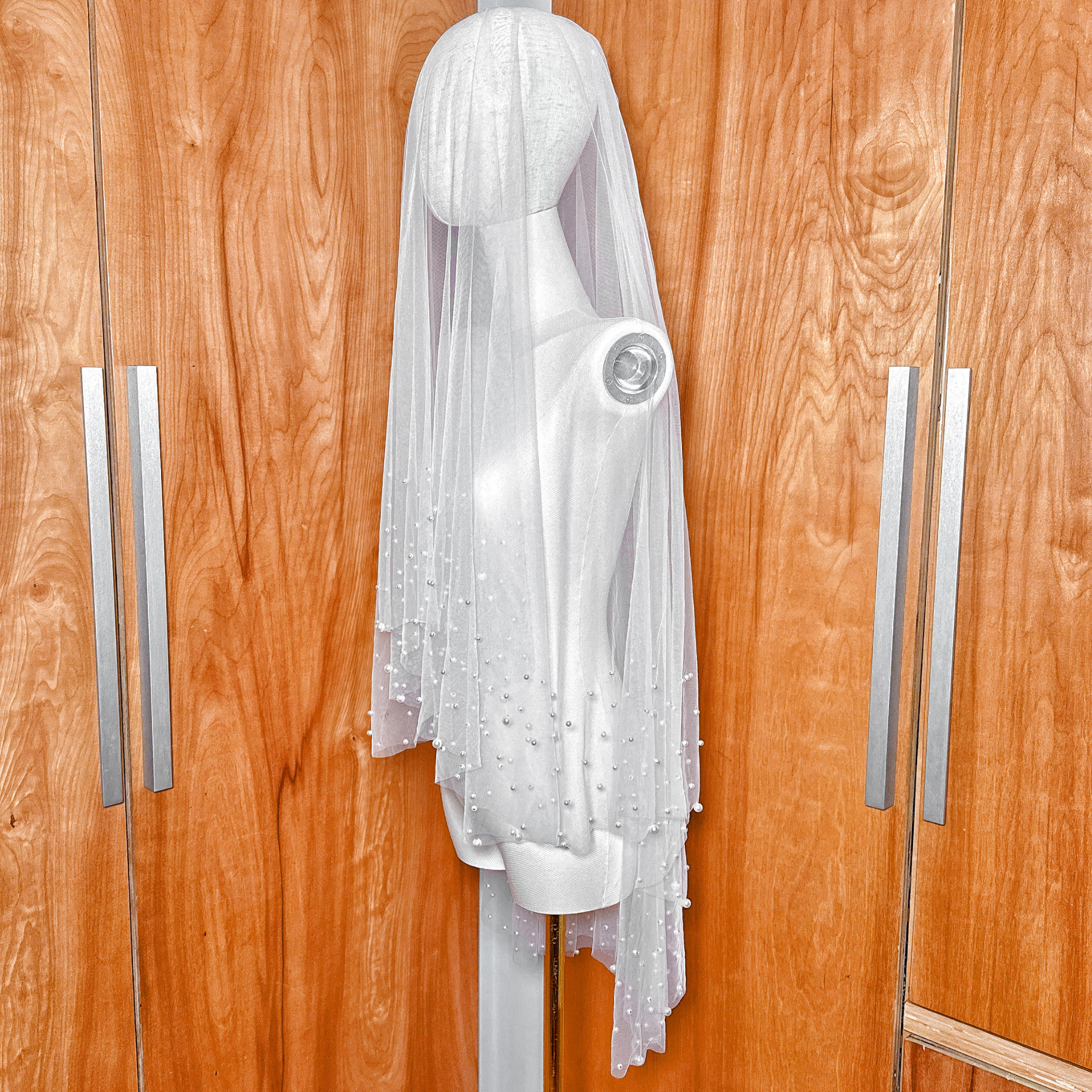 Side profile of a luxury two tier scattered pearl wedding veil in a classic fingertip length.