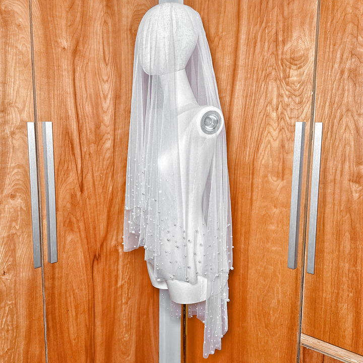 Side profile of a luxury two tier scattered pearl wedding veil in a classic fingertip length.