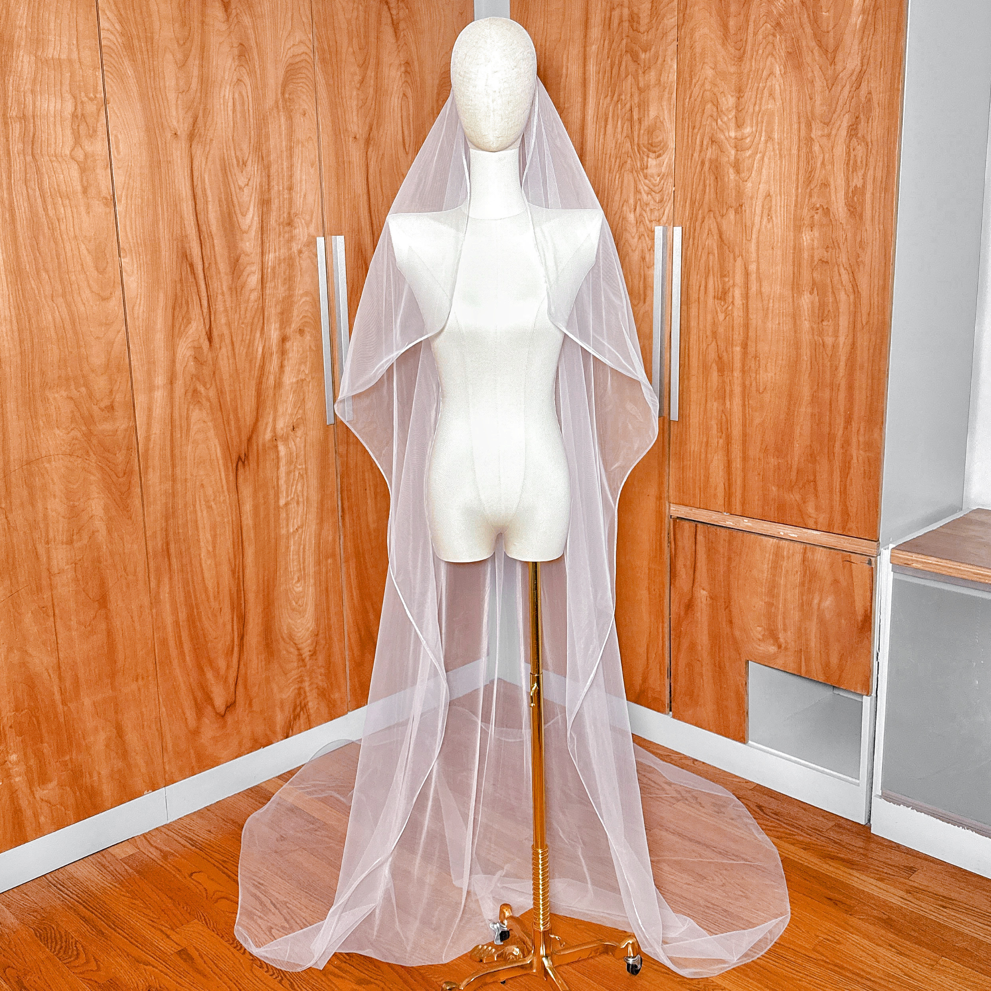 Full-length view of a cathedral cascade wedding veil with structured 1/8 horsehair trim draped over a mannequin.