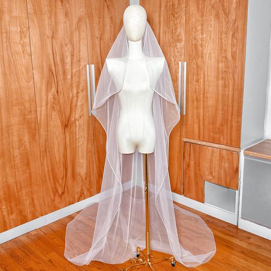 Full-length view of a cathedral cascade wedding veil with structured 1/8 horsehair trim draped over a mannequin.