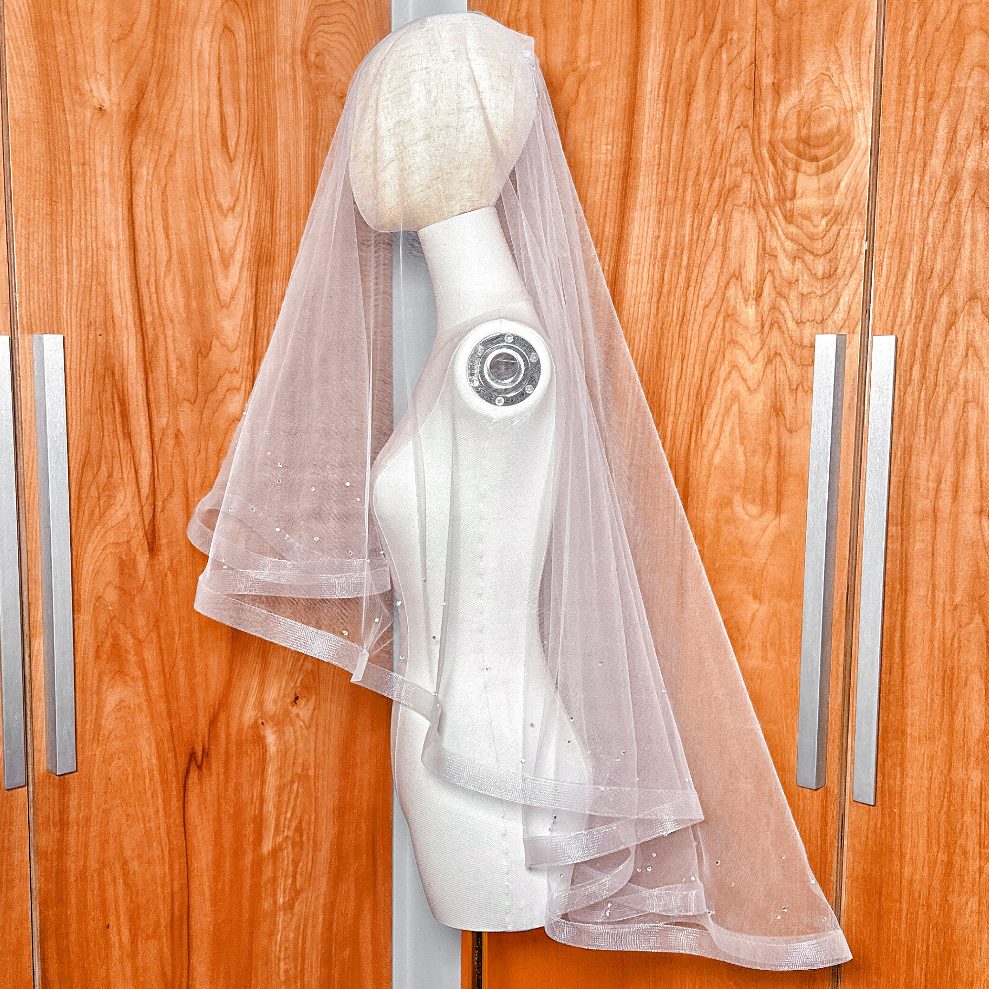 Side profile of a two tier horsehair wedding veil with scattered rhinestones draped over a mannequin.