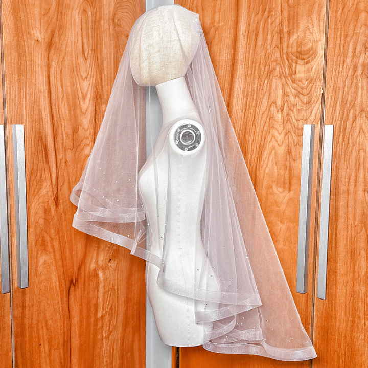 Side profile of a two tier horsehair wedding veil with scattered rhinestones draped over a mannequin.
