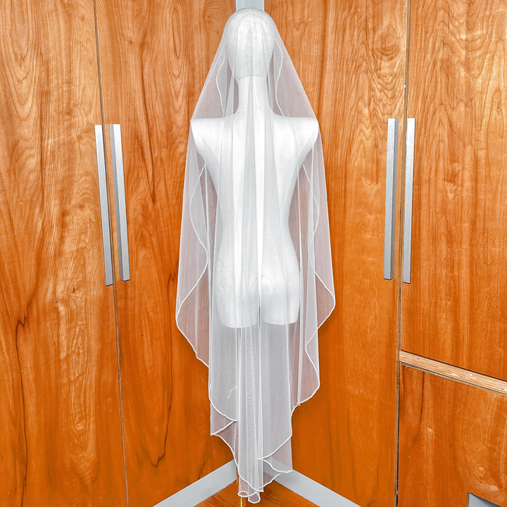 Rear view of a waltz length pearl mantilla veil on a mannequin, demonstrating the sheer quality of the tulle and the even distribution of hand-placed pearls.