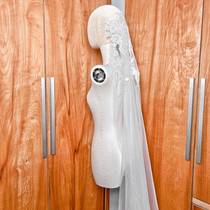 Side profile of a cathedral length beaded lace mantilla veil on a mannequin, illustrating how the lace drapes elegantly over the shoulders.