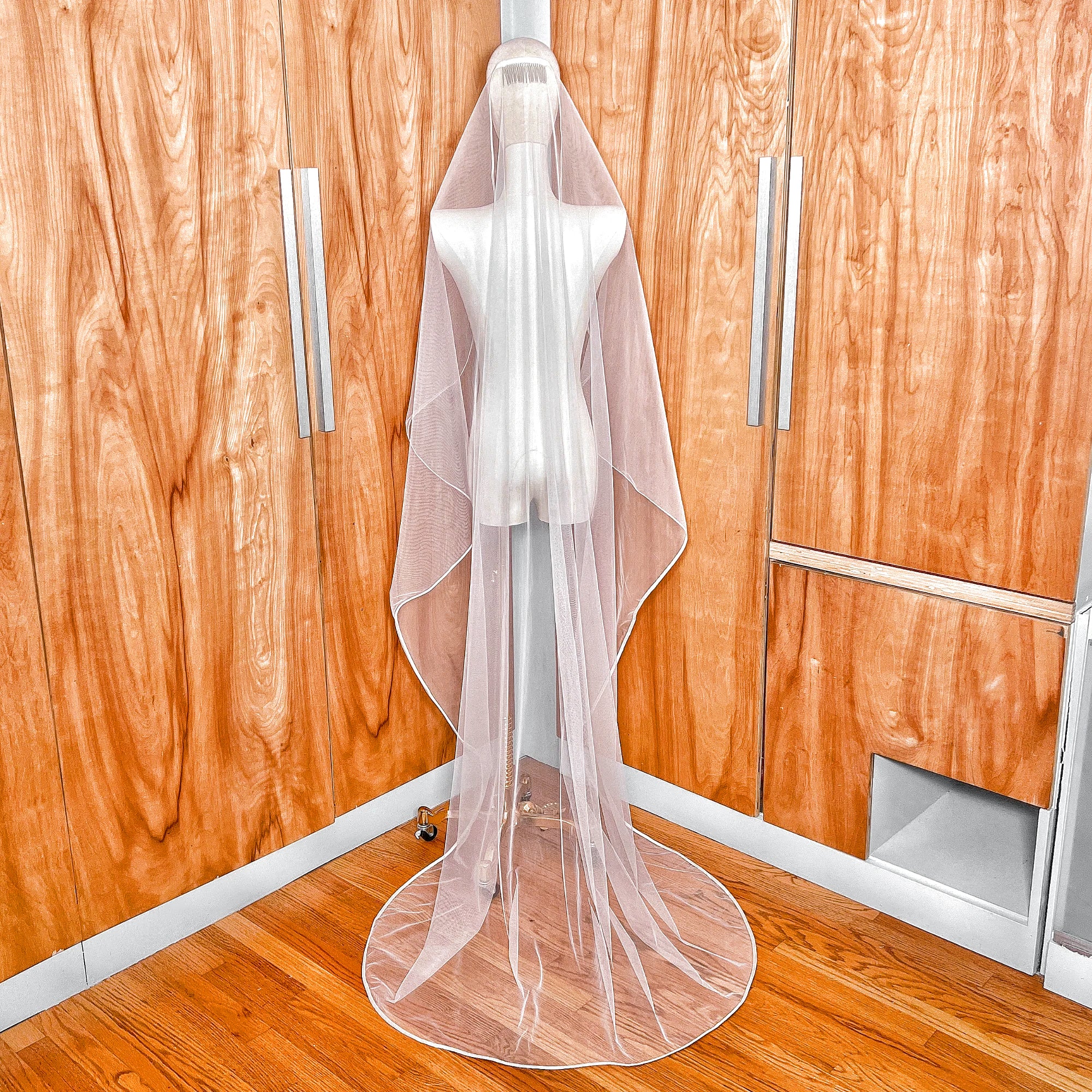 Back view showing the full length and elegant drape of the mantilla wedding veil with ribbon trim on a mannequin.