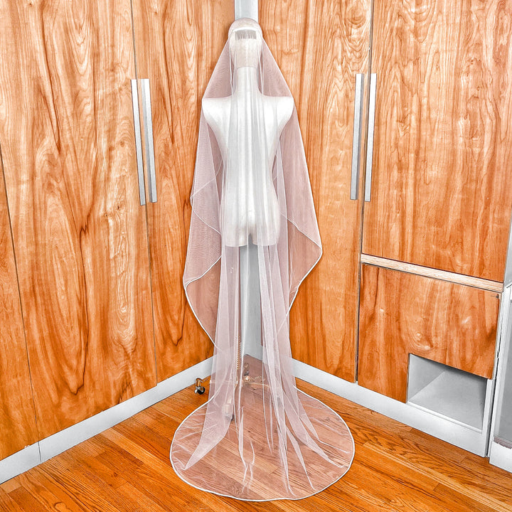 Back view showing the full length and elegant drape of the mantilla wedding veil with ribbon trim on a mannequin.