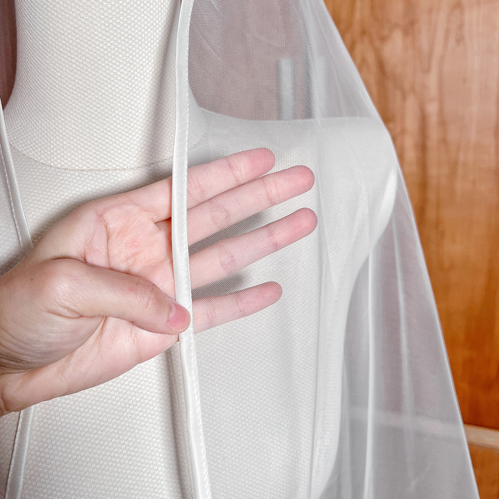 Close-up of the delicate ribbon trim and soft tulle texture on the mantilla wedding veil.