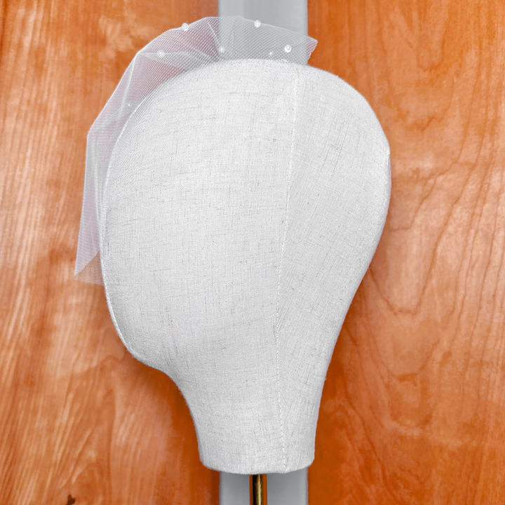 Side view showing the drape and shape of the ivory mini birdcage wedding veil with pearls.