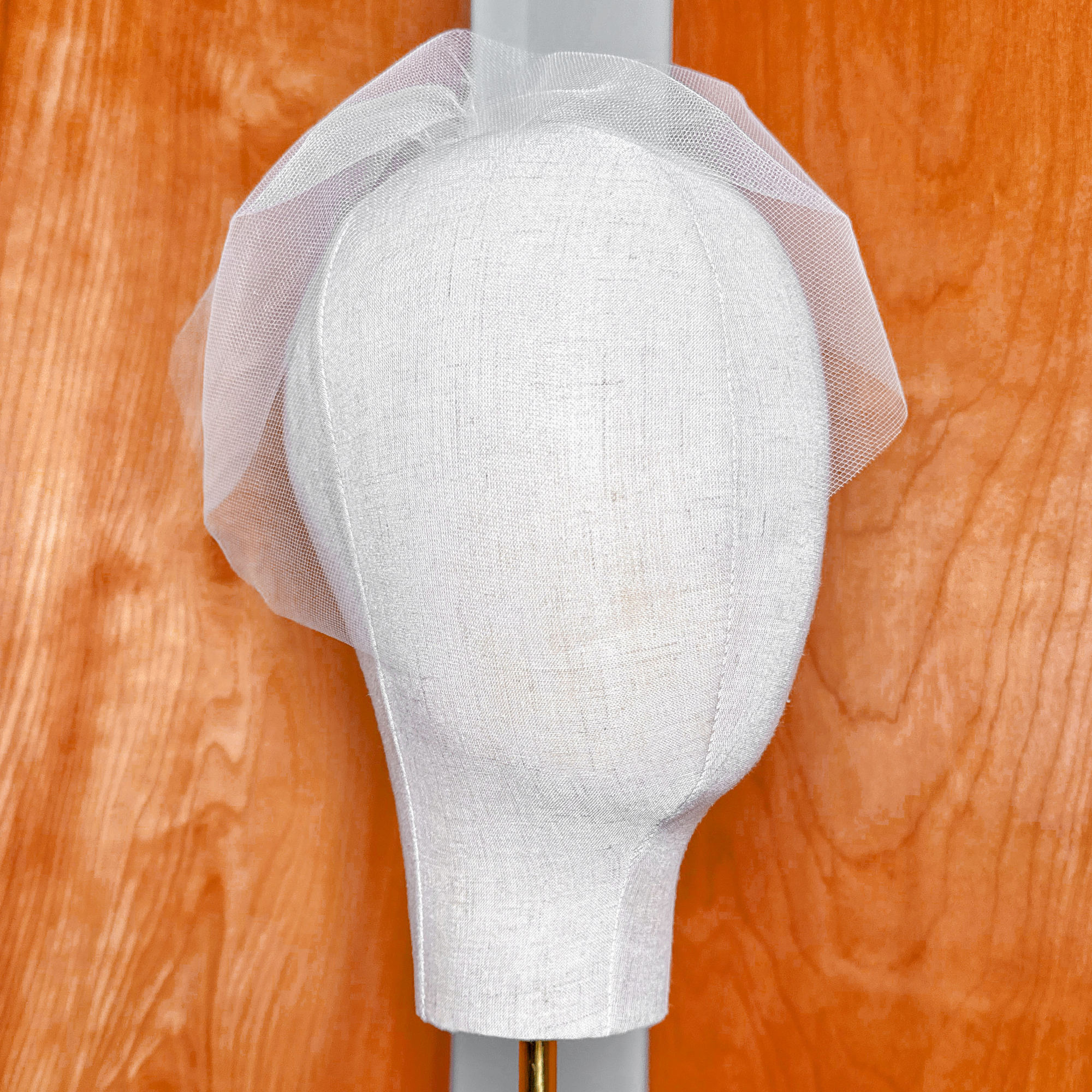 Front view of a short blusher-style mini tulle birdcage wedding veil demonstrating the sheer facial coverage and structure.