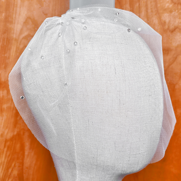 Close up view of a mini tulle birdcage wedding veil with rhinestones and pearls.