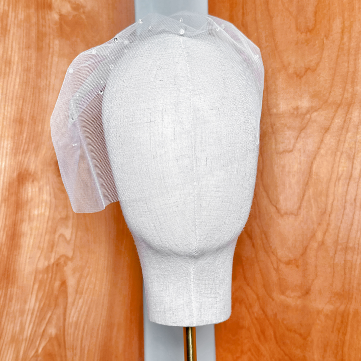 Front view of a bridal mini tulle birdcage wedding veil with rhinestones and pearls.