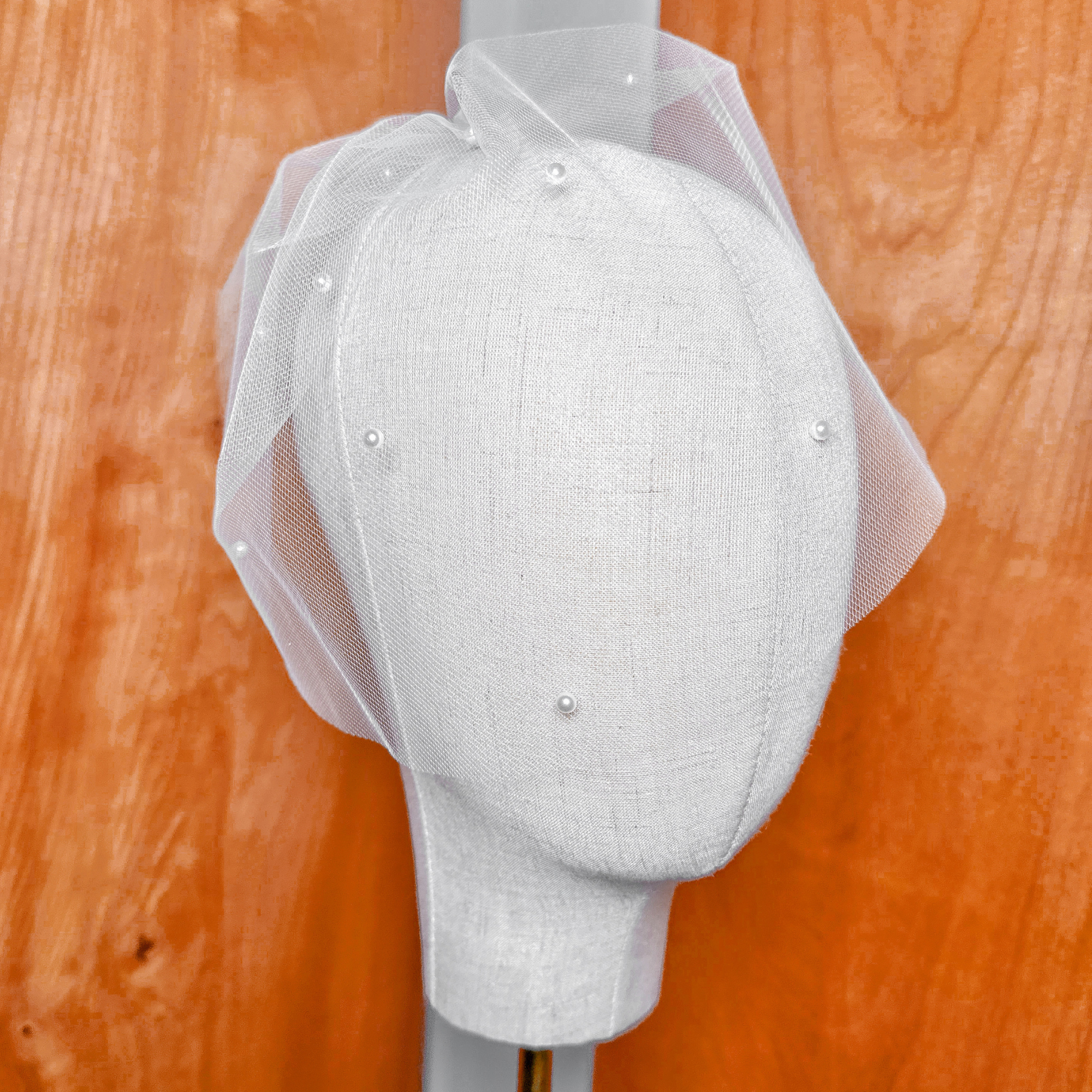Macro close-up of the delicate netting and pearl embellishments on the mini tulle birdcage wedding veil.